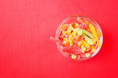 çok renkli bir cam kase kırmızı bir arka plan üzerinde kurutulmuş ananas parçaları