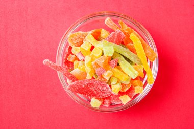 çok renkli bir cam kase kırmızı bir arka plan üzerinde kurutulmuş ananas parçaları