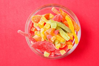 çok renkli bir cam kase kırmızı bir arka plan üzerinde kurutulmuş ananas parçaları