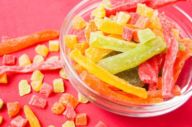 çok renkli bir cam kabın içinde ve yakın kase kırmızı bir arka plan üzerinde kurutulmuş ananas parçaları