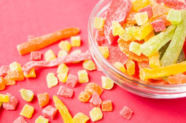 çok renkli bir cam kabın içinde ve yakın kase kırmızı bir arka plan üzerinde kurutulmuş ananas parçaları