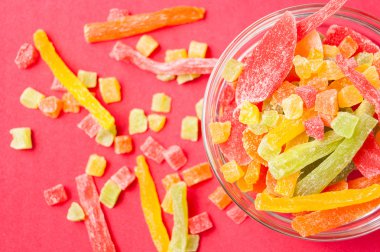 çok renkli bir cam kabın içinde ve yakın kase kırmızı bir arka plan üzerinde kurutulmuş ananas parçaları