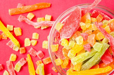 çok renkli bir cam kabın içinde ve yakın kase kırmızı bir arka plan üzerinde kurutulmuş ananas parçaları