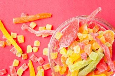 çok renkli bir cam kabın içinde ve yakın kase kırmızı bir arka plan üzerinde kurutulmuş ananas parçaları