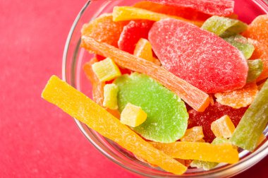 çok renkli bir cam kase kırmızı bir arka plan üzerinde kurutulmuş ananas parçaları