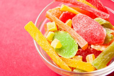 çok renkli bir cam kase kırmızı bir arka plan üzerinde kurutulmuş ananas parçaları