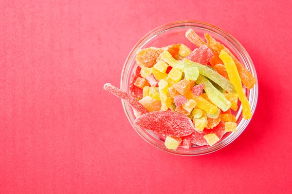 çok renkli bir cam kase kırmızı bir arka plan üzerinde kurutulmuş ananas parçaları