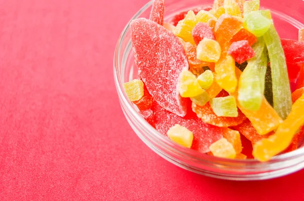 çok renkli bir cam kase kırmızı bir arka plan üzerinde kurutulmuş ananas parçaları