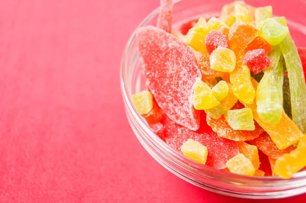 çok renkli bir cam kase kırmızı bir arka plan üzerinde kurutulmuş ananas parçaları