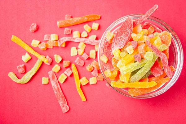 çok renkli bir cam kabın içinde ve yakın kase kırmızı bir arka plan üzerinde kurutulmuş ananas parçaları