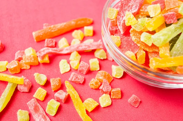 çok renkli bir cam kabın içinde ve yakın kase kırmızı bir arka plan üzerinde kurutulmuş ananas parçaları