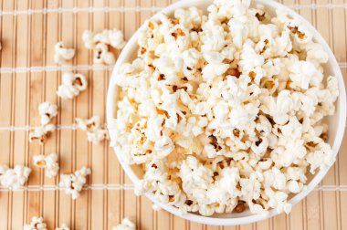 Beyaz bir kase patlamış mısır ve mindere döktüm