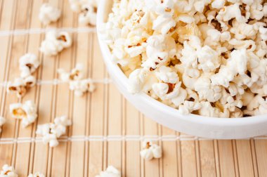 Beyaz bir kase patlamış mısır ve mindere döktüm