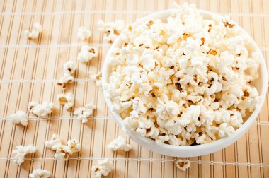 Beyaz bir kase patlamış mısır ve mindere döktüm