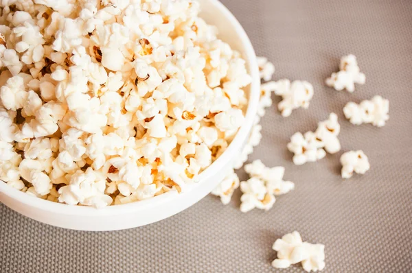 Popcorn in a white bowl on a gray background and spilled popcorn Royalty Free Stock Photos