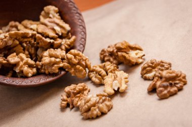 Kağıt üzerinde kahverengi seramik kase üzerinden dökülen ceviz badem