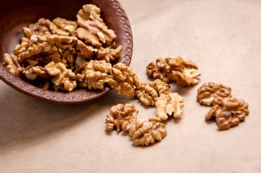 Kağıt üzerinde kahverengi seramik kase üzerinden dökülen ceviz badem