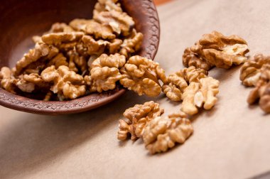 Kağıt üzerinde kahverengi seramik kase üzerinden dökülen ceviz badem