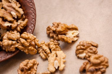 Kağıt üzerinde kahverengi seramik kase üzerinden dökülen ceviz badem