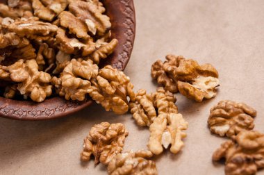 Kağıt üzerinde kahverengi seramik kase üzerinden dökülen ceviz badem