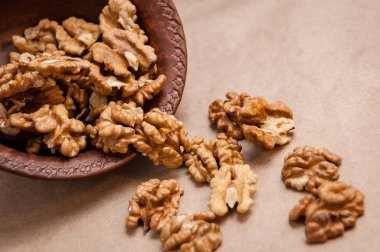 Kağıt üzerinde kahverengi seramik kase üzerinden dökülen ceviz badem