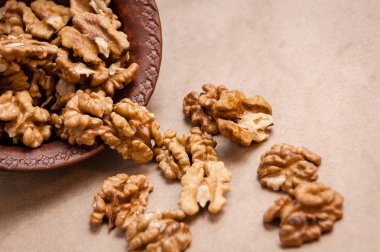 Kağıt üzerinde kahverengi seramik kase üzerinden dökülen ceviz badem