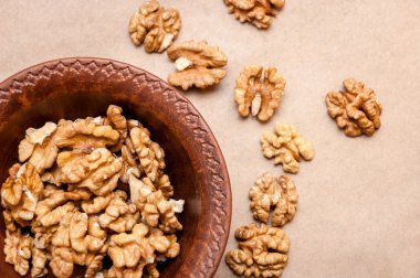 Kağıt üzerinde bir kahverengi çanak çömlek kapta ceviz taneleri