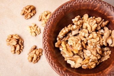 Kağıt üzerinde bir kahverengi çanak çömlek kapta ceviz taneleri