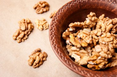 Kağıt üzerinde bir kahverengi çanak çömlek kapta ceviz taneleri