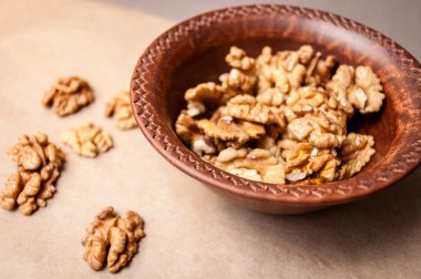 Kağıt üzerinde bir kahverengi çanak çömlek kapta ceviz taneleri