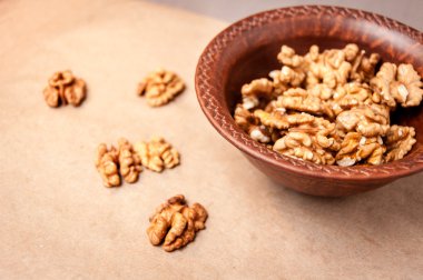 Kağıt üzerinde bir kahverengi çanak çömlek kapta ceviz taneleri