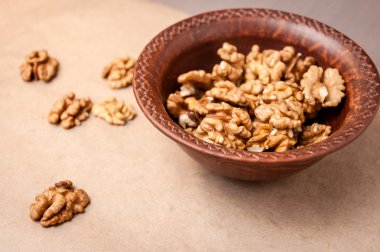 Kağıt üzerinde bir kahverengi çanak çömlek kapta ceviz taneleri