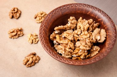 Kağıt üzerinde bir kahverengi çanak çömlek kapta ceviz taneleri