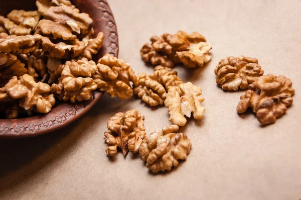 Kağıt üzerinde kahverengi seramik kase üzerinden dökülen ceviz badem