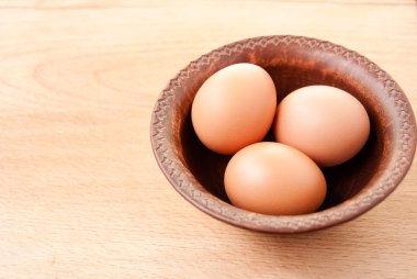 Ahşap masa üzerinde seramik kase tavuk yumurtası