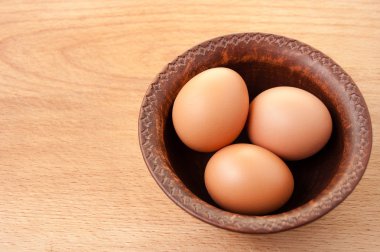 Ahşap masa üzerinde seramik kase tavuk yumurtası