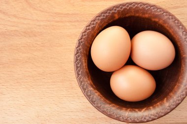 Ahşap masa üzerinde seramik kase tavuk yumurtası