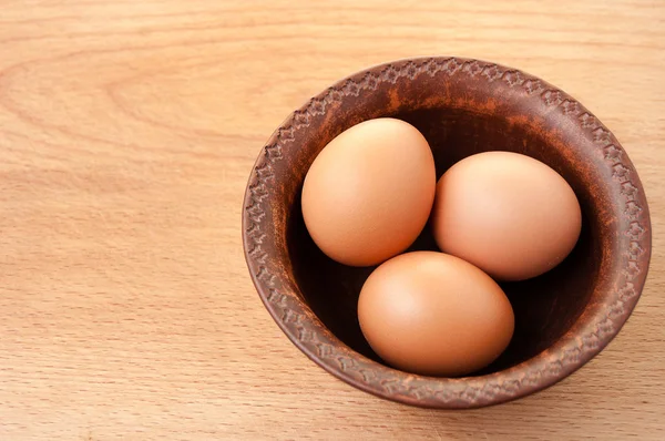 Ahşap masa üzerinde seramik kase tavuk yumurtası
