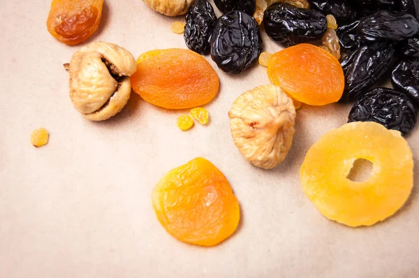 dried fruits, dried pineapple, dried figs, walnuts, prunes, figs, dried apricots on a paper, top view