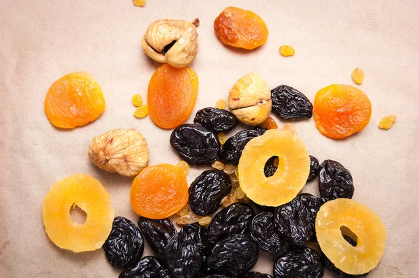 dried fruits, dried pineapple, dried figs, walnuts, prunes, figs, dried apricots on a paper, top view