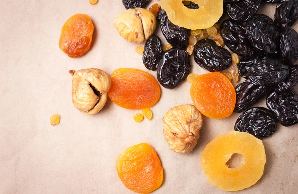 dried fruits, dried pineapple, dried figs, walnuts, prunes, figs, dried apricots on a paper, top view