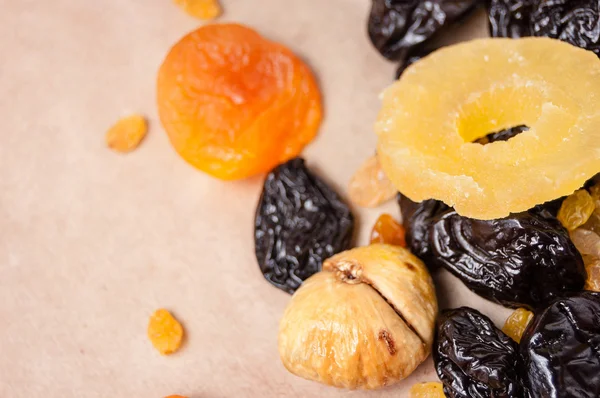 dried fruits, dried pineapple, dried figs, walnuts, prunes, figs, dried apricots on a paper, top view