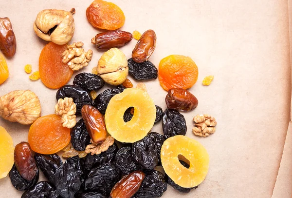 dried fruits, dried pineapple, dried figs, walnuts, prunes, figs, dried apricots on a paper, top view