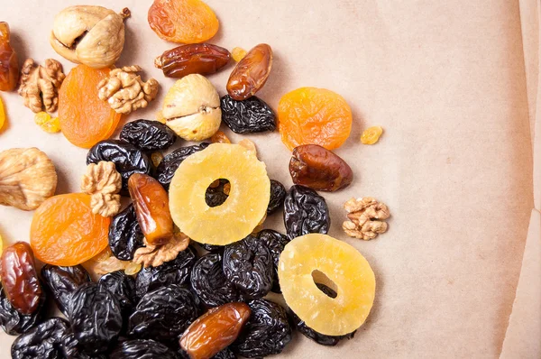 dried fruits, dried pineapple, dried figs, walnuts, prunes, figs, dried apricots on a paper, top view