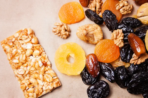 dried fruits, dried pineapple, dried figs, walnuts, prunes, figs, dried apricots on a paper, top view