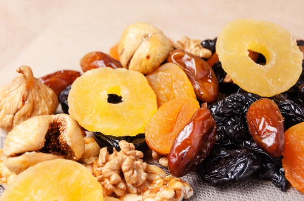 dried fruits, dried pineapple, dried figs, walnuts, prunes, figs, dried apricots on a paper, top view