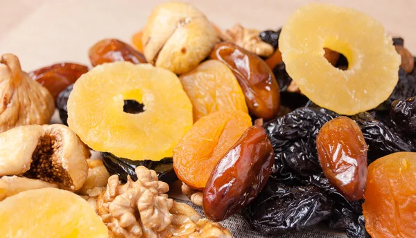 dried fruits, dried pineapple, dried figs, walnuts, prunes, figs, dried apricots on a paper, top view