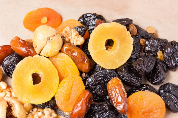 dried fruits, dried pineapple, dried figs, walnuts, prunes, figs, dried apricots on a paper, top view