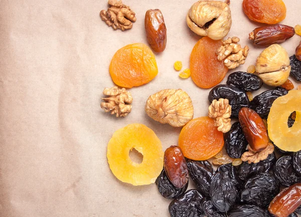 dried fruits, dried pineapple, dried figs, walnuts, prunes, figs, dried apricots on a paper, top view
