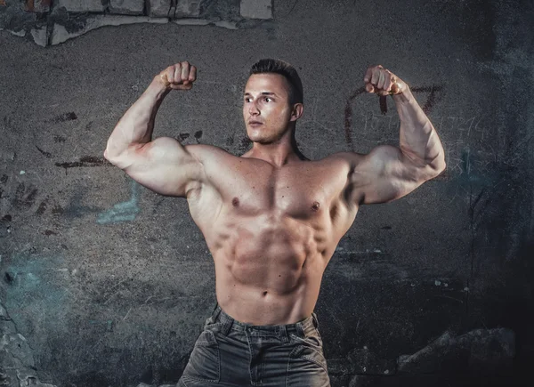 Bodybuilder op grunge muur — Stockfoto